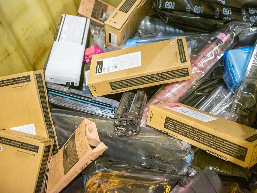 Tonere kastet i container sammen med papp. Foto.